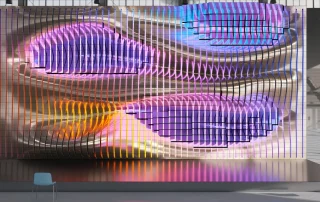 Large curved kinetic LED screen art installation with colourful lighting